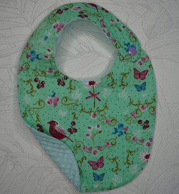 Bavoir bébé tissu fond vert avec des papillons, oiseaux et fleurs