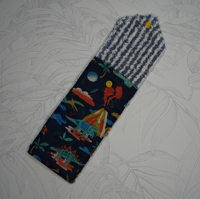 Pochette brosse à dents et dentifrice tissu bleu foncé avec des dinosaures et volcans dans des couleurs vives et tissu éponge rayé bleu foncé et blanc