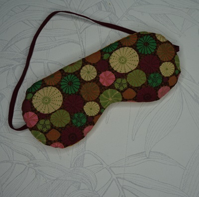 Masque yeux aux graines tissu marron avec des cercles vert, beige, rose et violet.